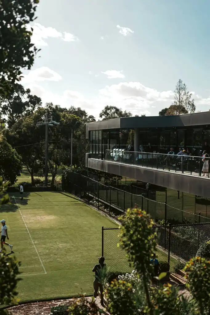 Outdoor tennis court next to modern pavilion architecture under daylight