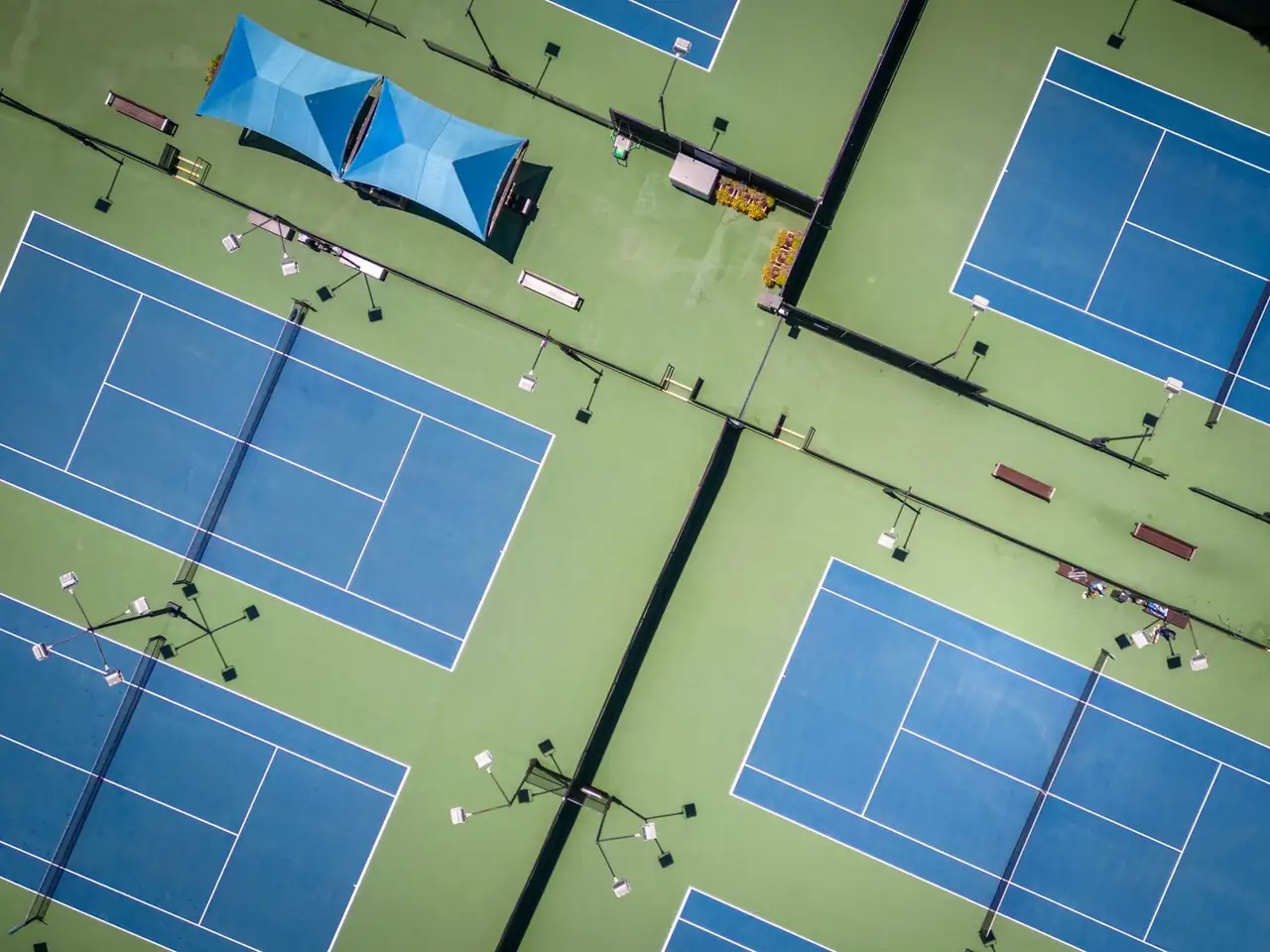 Aerial perspective of structured geometric tennis court surfaces and boundaries