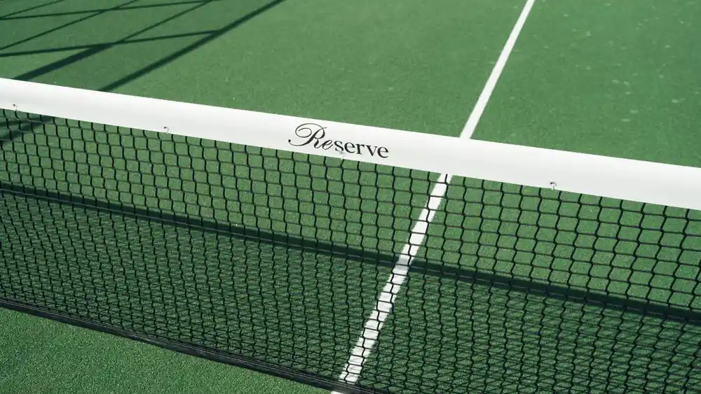 Detail of a pristine tennis court net and white boundary lines on a green recreational court