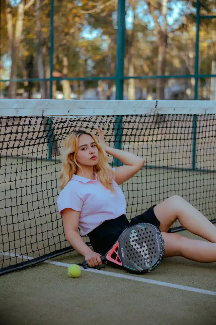 Confident tennis player relaxing on court in proper tennis sportswear with racket